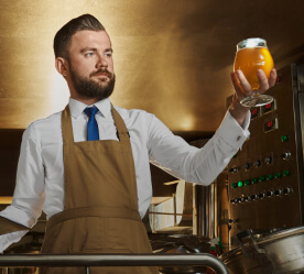 man holding up glass full of beer
