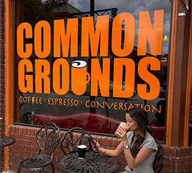 Taylor drinking her coffee at the bistro table in front of the downtown Common Grounds