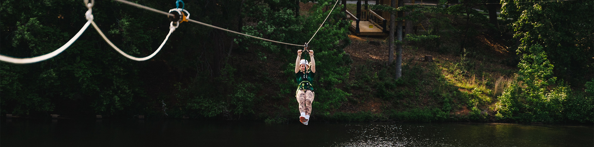 a girl on a zipline above a lake