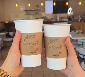 a girl holding 2 to-go coffee cups with logo on them