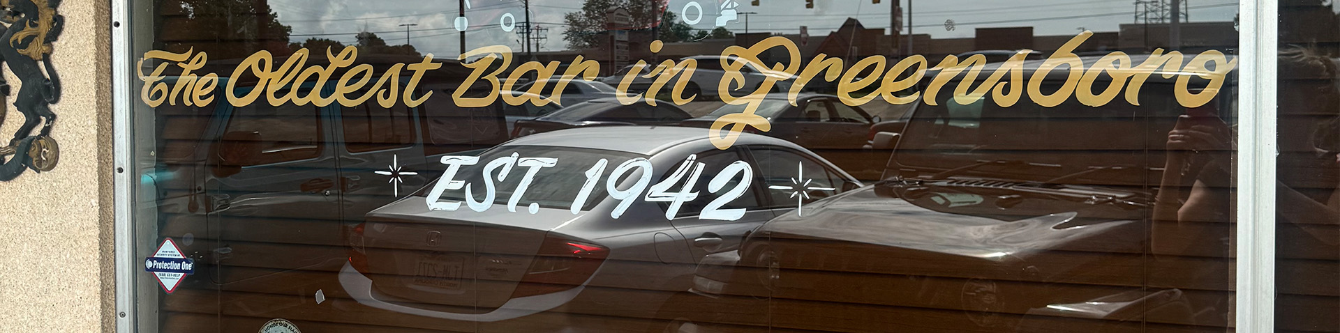 close-up of exterior window saying it's the oldest bar in Greensboro