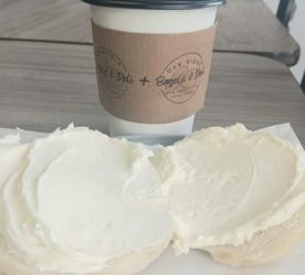 close-up of sleeve on coffee cup and bagel with cream cheese