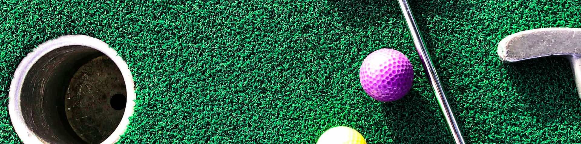 golf clubs and colorful balls on mini golf course