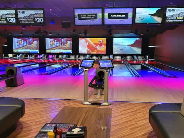 the bowling alley lit up with colors and TVs in the background