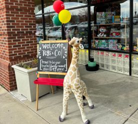 a giraffe and balloons with a sign that says that the store is locally-owned for 45 years