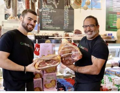 owner and son of Giacamo's holding up meat