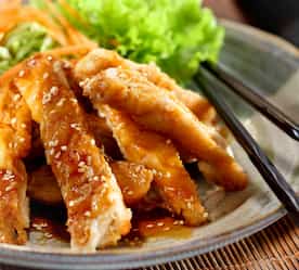 strips of chicken with lettuce in background and chop sticks
