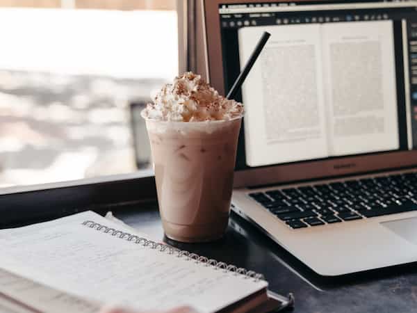coffee drink with whipped cream and topping by laptop