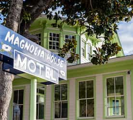 close-up of sign with historic magnolia house in background