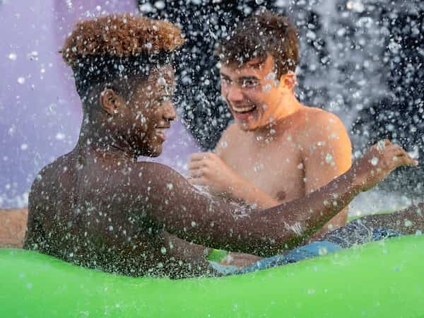 two guys in water float with water splashing