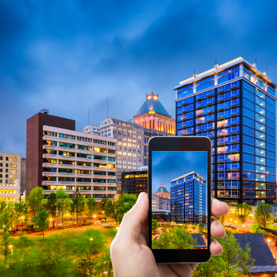 Greensboro Skyline with hand holding cellphone